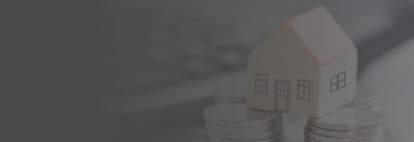 A small toy house atop a stack of coins on an accountants desk